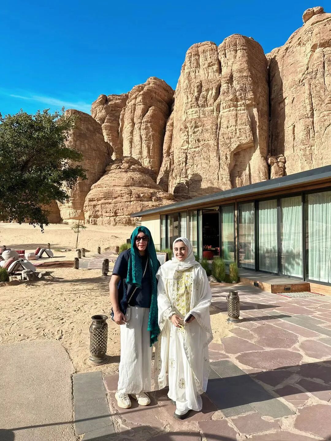People and hospitality spaces beside the sandstone cliffs.