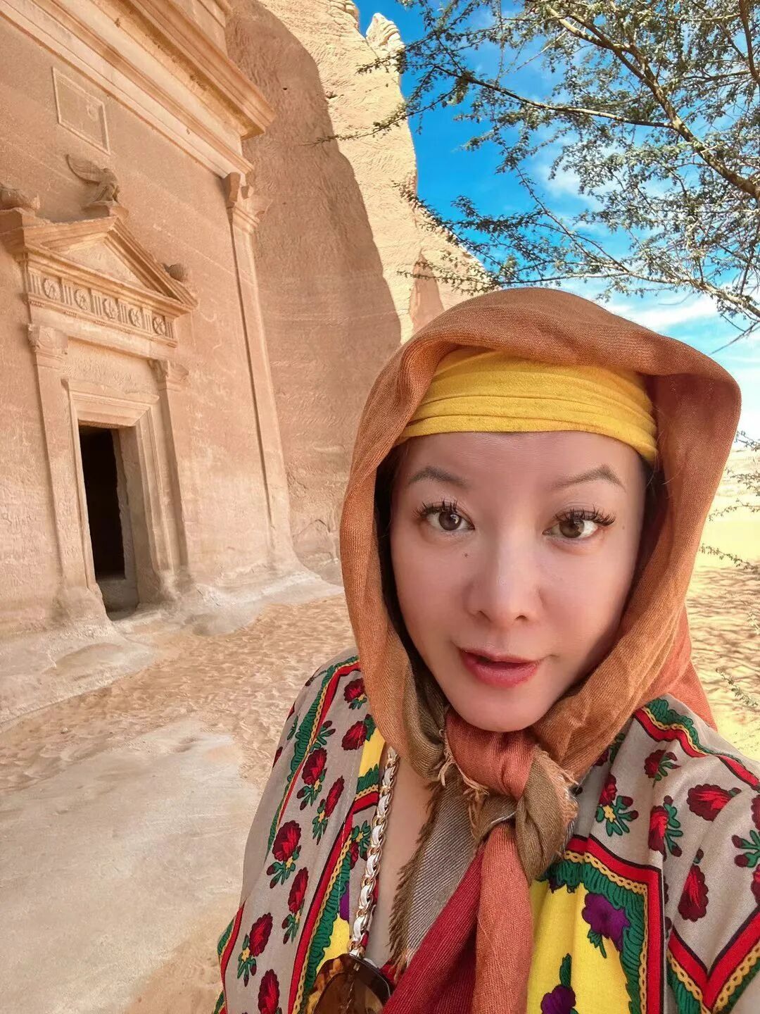 Standing beside a carved tomb entrance.
